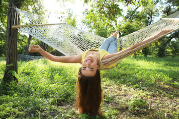 Wall Mural - Young woman resting in comfortable hammock at green garden