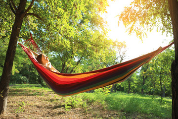 Wall Mural - Young woman resting in comfortable hammock at green garden