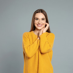 Canvas Print - Beautiful young woman in yellow sweater on grey background. Winter season