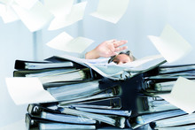 Desperate Woman Behind High Stacks Of Ring Binders And Lots Of Papers Are Flying Around In The Office, Concept Of Excessive Demands And Increasing Work In Business