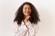 © Anatoliy Karlyuk - Portrait of attractive stylish young African American female in striped pajamas clasping hands and looking away with mysterious playful facial expression as if expecting for something good to happen