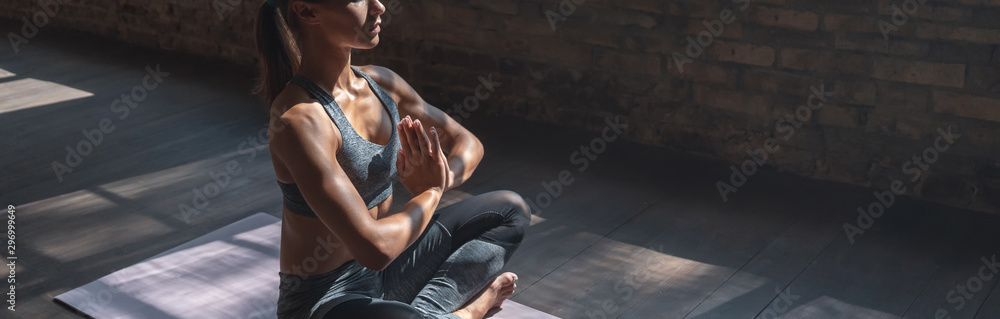 Calm fit sporty healthy mindful woman sit in lotus pose doing yoga exercise breathing fresh air meditating in gym lit with sunlight, stress free concept, horizontal banner website design, copy space - obrazy, fototapety, plakaty 
