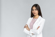 Serious young adult indian businesswoman in white formal wear crossed arm on chest and looking at camera. Woman standing isolated on grey background with copy space
