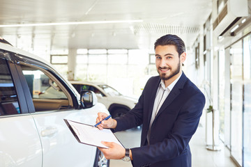 Canvas Print - A car dealer is holding documents on the sale of a car.