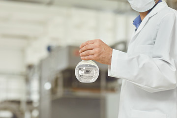 The flask with the water test in the hands of the technologist on the factory.