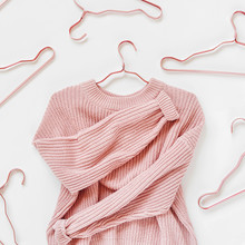 Pale Pink Knitted Sweater With Metallic Hangers On White Background. Autumn And Winter Clothes. Store, Sale, Fashion Concept.