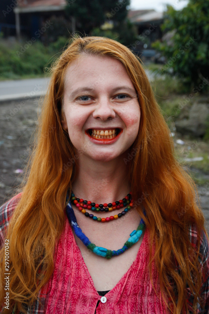 woman chewing tobacco A young Caucasian woman with red hair chews traditional Asian tobacco -  betel leaves, which makes her mouth bright red. Woman shows teeth. Stock  Photo