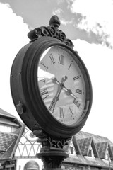 Poster - Vertical grayscale of a steel analog clock on a pole on a street