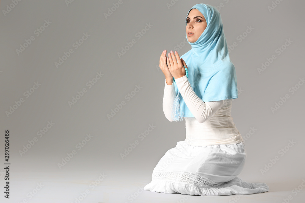 Praying Muslim woman on grey background