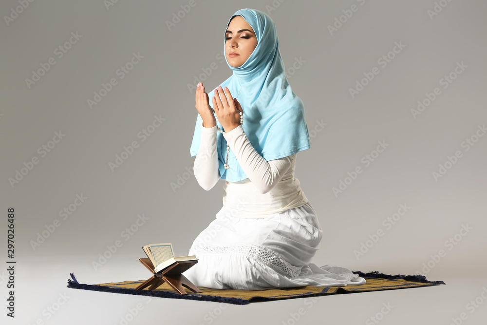 Praying Muslim woman on grey background