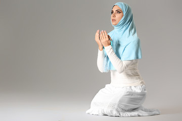 Wall Mural - Praying Muslim woman on grey background