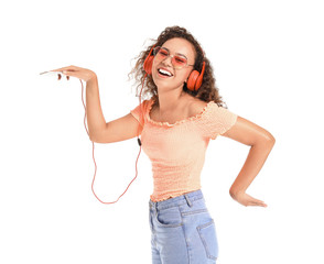 Wall Mural - Beautiful African-American woman dancing and listening to music on white background