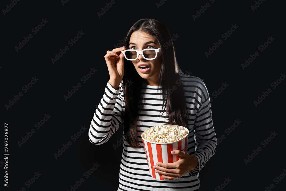 Shocked woman with popcorn on dark background