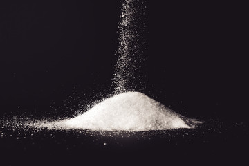 Pouring of sand sugar onto dark background