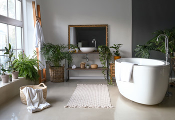 Stylish interior of bathroom with green houseplants