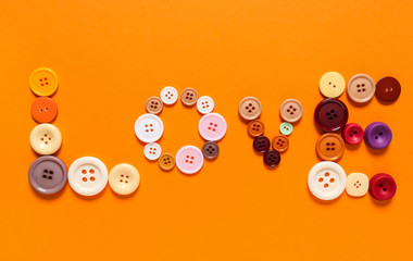 Word LOVE made of buttons on color background