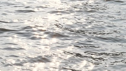 Wall Mural - Golden glisten of sunlight reflects on the sunrise sea surface. Sparkling sunlight over the calm water. Super slow motion footage.