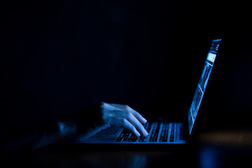 hand of a man using laptop computer for hacking or steal data at night in office. hacking concept