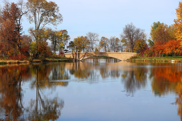 Wall Mural - beautiful fall landscape with a bridge in the city park.scenic view with colored trees around old st