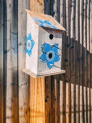 birdhouse with blue flower hanging on wood fence