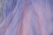 Close up of thin blue tulle fabric on pink background