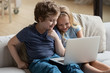 © fizkes - Little boy and girl using laptop, watching cartoons or playing