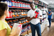 © JackF - focused muscular African man choosing sports nutrition products in shop, reading content label