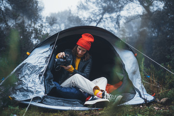 Wall Mural - photographer tourist traveler take photo on camera in camp tent in foggy rain forest, hiker woman shooting mist nature trip, trekking tourism, rest vacation