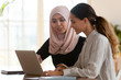 © fizkes - Asian muslim female mentor teaching caucasian intern explaining computer work