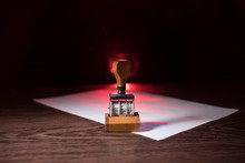 Close Up View Of Rubber Date Stamper On Wooden Table With Dark Toned Foggy Background.
