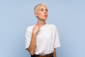 Teenager girl with white short hair over blue wall with tired and sick expression