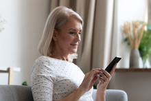 Happy Middle Aged Woman Using Mobile Apps Texting At Home