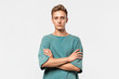 © ianachyrva - Confedent young man in a green tee holds hands folded isolated over grey background.