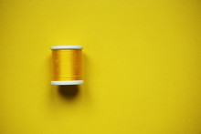 Yellow Spool Of Thread On Yellow Background. Minimal Aesthetic.