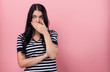 © Tierney - Young woman covering her mouth on a pink background