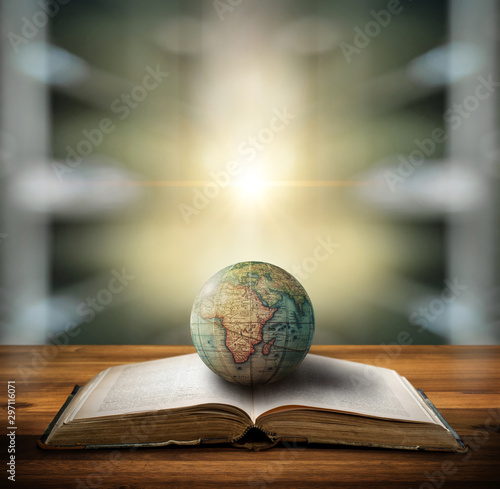 An old globe lying on an open book against the background of library. Selecti...