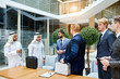 © alfa27 - Positive interpreter between businessmen, sheikh and caucasian. Sheikh holding white case, caucasian black case. Translator of arabic and english languages