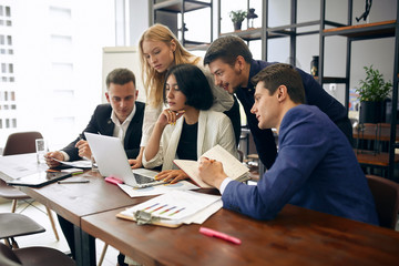 young brunette leader and her colleagues surfing , browsing the internet,close up side view photo