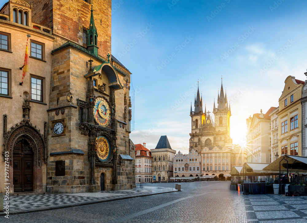 Bllick auf die Astronomische Uhr am Rathaus und die Marienkirche am zentralen Platz der Altstadt bei Sonnenaufgang ohne Menschen, Prag, Tschechien - obrazy, fototapety, plakaty 