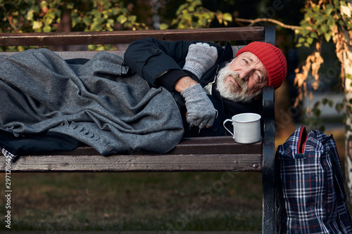 Fotomural Roofless male lying on street bench asking for money, for any help