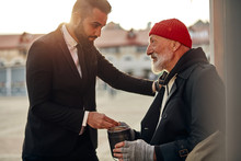 Man In Tuxedo Came Up To Beggar To Help, Give Money Donation. Rich Man Hold Out His Hand With Money To Homeless Person. People Relationship Concepr