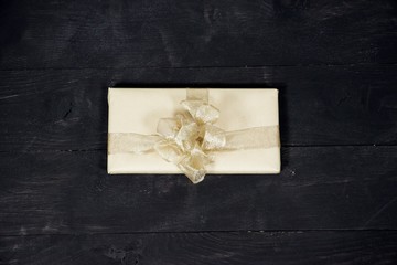 Poster - Aerial shot of a present with a golden ribbon and a bow on a wooden surface