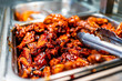 Barbeque sauce chicken wings buffet bar self serve with tongs in grocery store, restaurant or catering event with red color unhealthy food