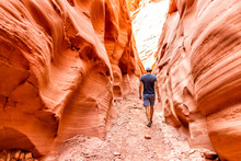 Man Hiker Walking By Red Wave Shape Formations At Antelope Slot Canyon In Arizona On Footpath Trail From Lake Powell