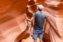 Orange Red Wave Shape Abstract Formations Rocks With Man Walking Touching Narrow Antelope Slot Canyon In Arizona On Path Footpath Trail From Lake Powell