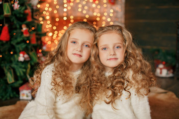 Merry Christmas and happy New Year. Happy little sisters on the background of Christmas decorations and gifts