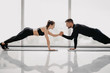 © F8  \ Suport Ukraine - Young sporty couple working out together in a gym doing plank exercises while holding each other for one hand.