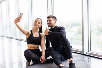 Wall Mural - Young fitness couple taking a sefie in a gym