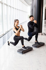 Wall Mural - Muscular fitness couple doing jumping squats in crossfit gym