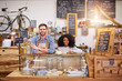 © marvent - Two smiling diverse baristas standing behind a cafe counter